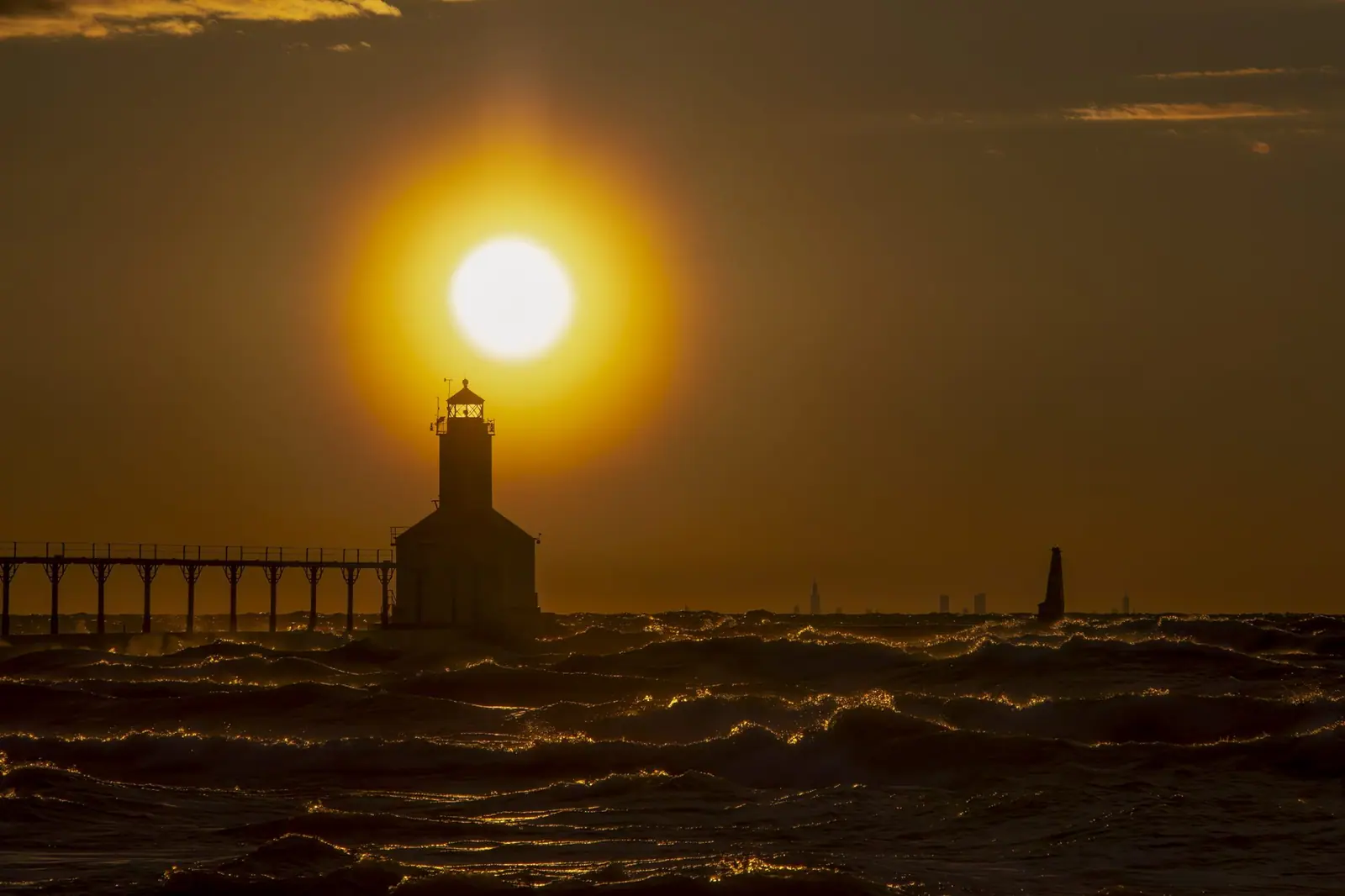 Michigan City lighthouse silhouetted against the setting sun over Lake Michigan