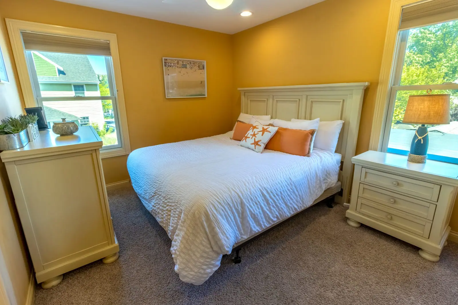 Bright guest bedroom with a king bed, cream furniture and two windows