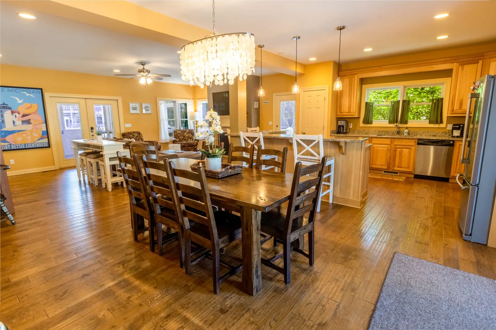 Dining table for a big group under a chandelier, next to the kitchen
