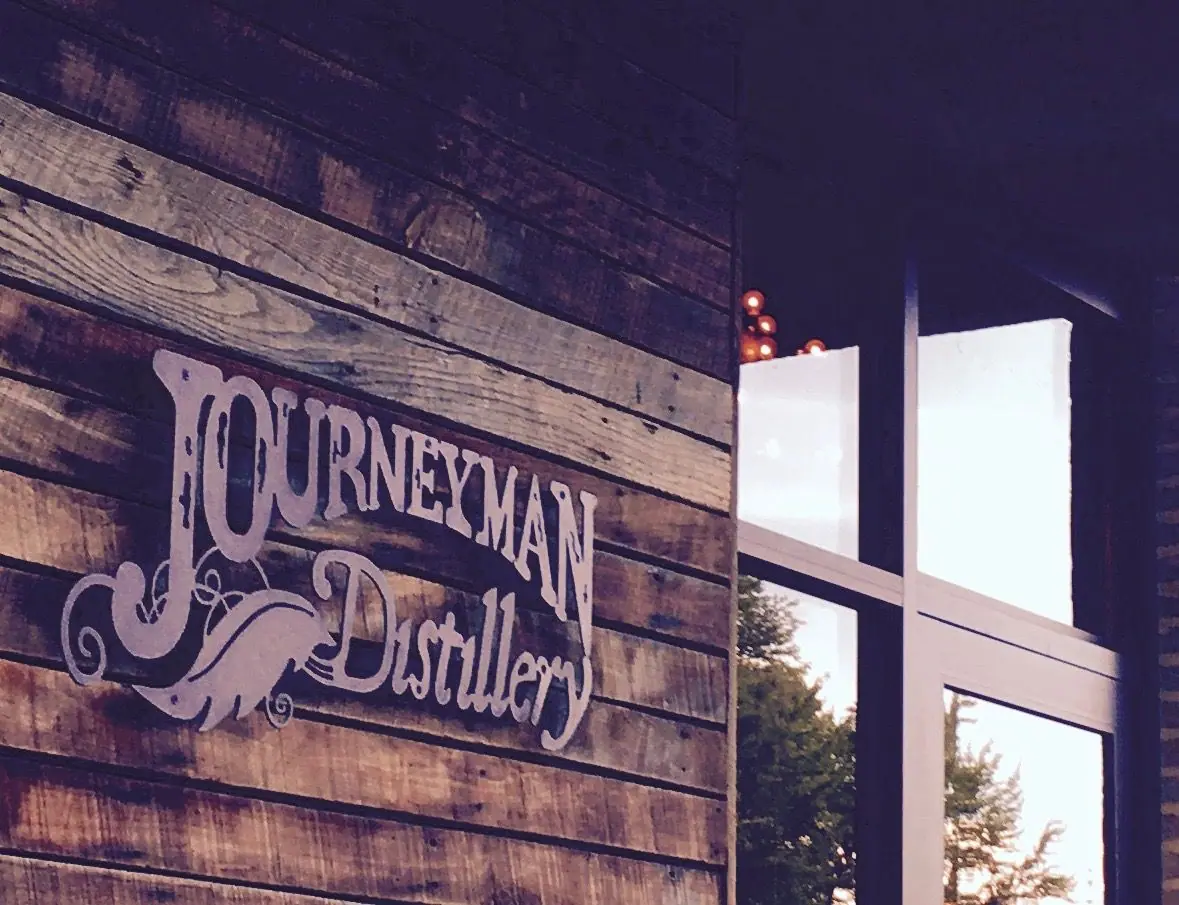 Journeyman Distillery sign on a weathered wood wall