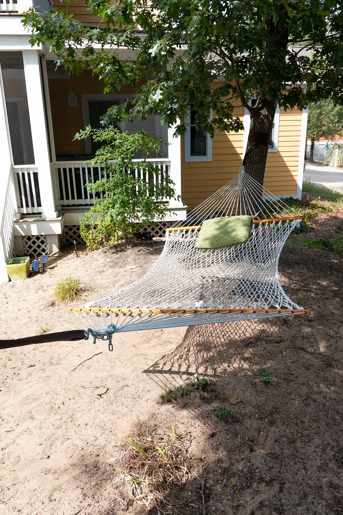 Rope hammock strung between trees in the sandy yard