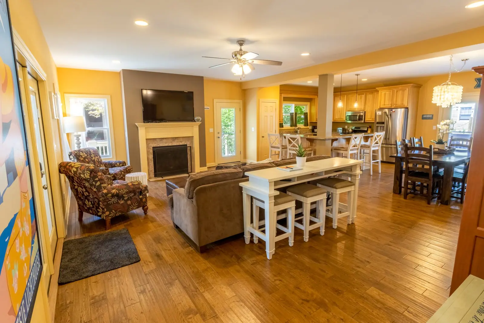 Open-plan living room with fireplace, sofa and bar table, flowing into the kitchen and dining area