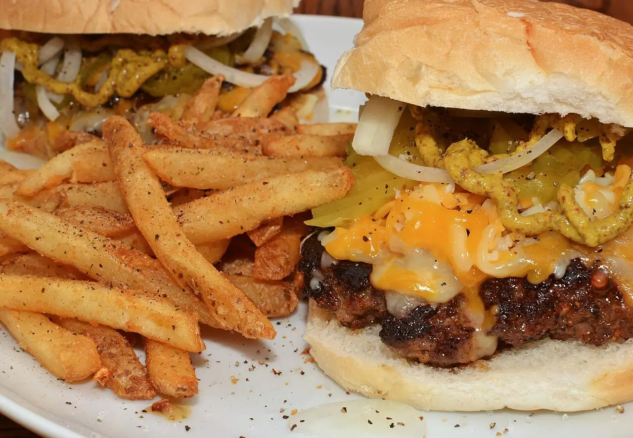 A cheeseburger with melted cheddar and a side of seasoned fries