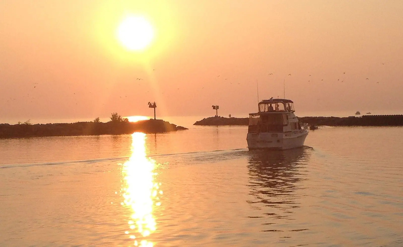 A boat heading into New Buffalo harbor at sunset