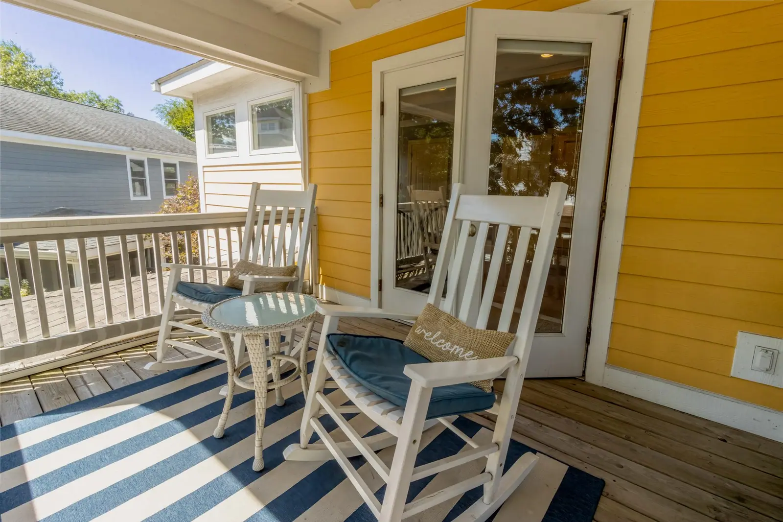 Private screened porch off the upstairs master with two white rocking chairs and a small table