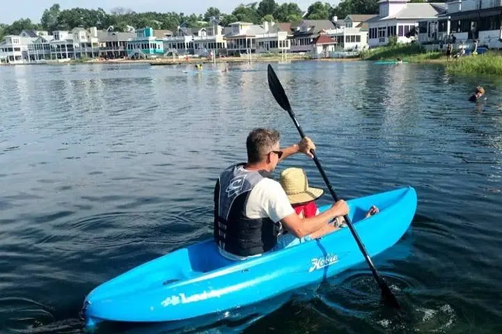 Parent and child paddling a turquoise kayak on Lake Kai