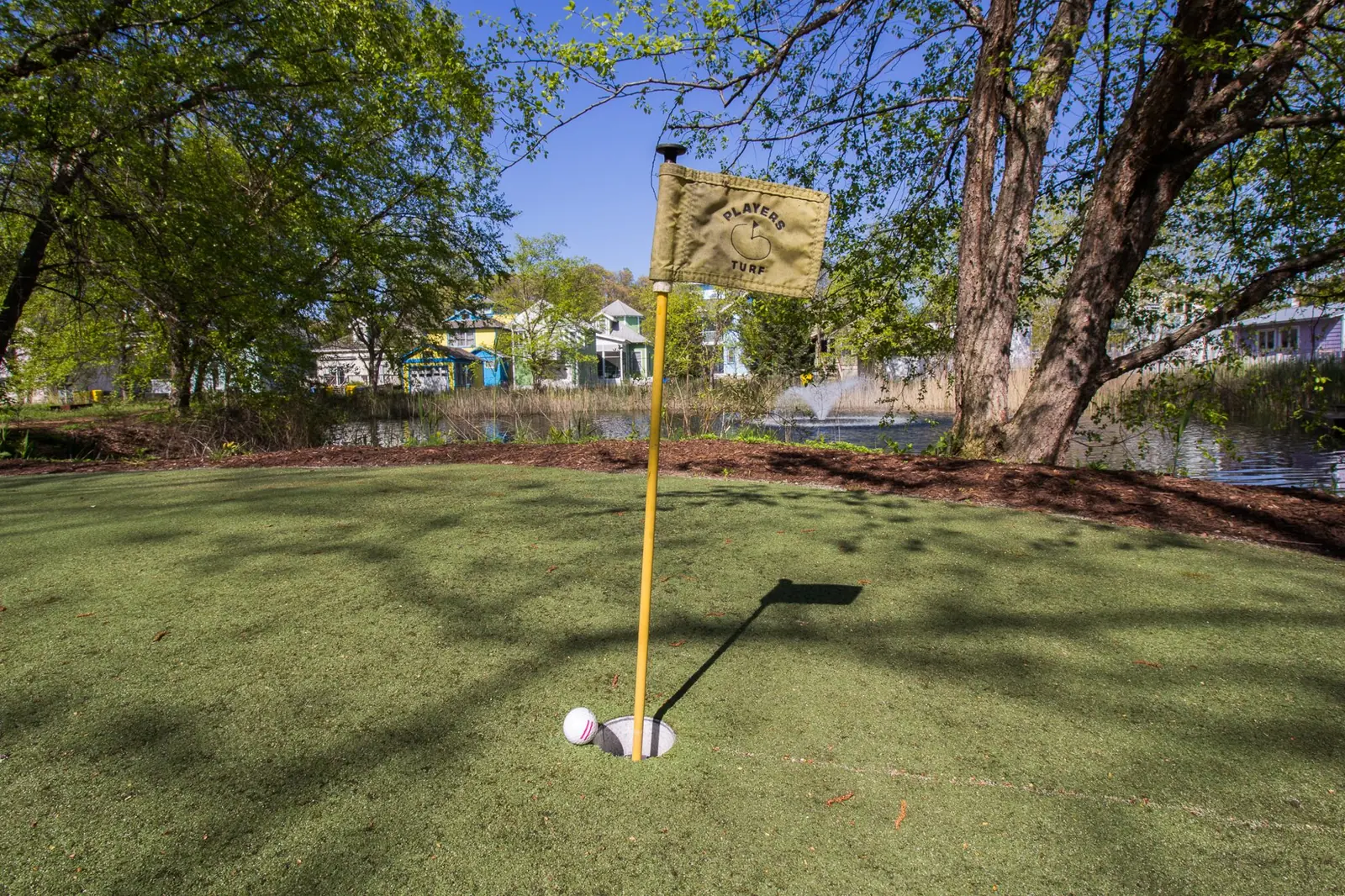 Putting green with a yellow flag in the shade
